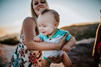 Мама, размахивая младенцем на руках и улыбаясь — стоковое фото