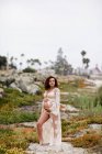 Junge schwangere Frau posiert im schlichten Kleid am Strand — Stockfoto