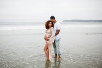 Casal de raça mista posando na praia, maternidade — Fotografia de Stock