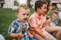 Hermanos con caras sucias comiendo helado juntos durante las vacaciones - foto de stock