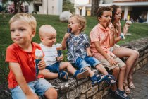 Niños y niñas comiendo helado juntos durante las vacaciones de verano - foto de stock