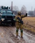 Ukraine modern soldier stops the car with a machine gun in his hands and an armored car — Foto stock