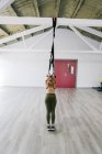 Mulher esportiva exercitando trx treinos de suspensão no ginásio — Fotografia de Stock