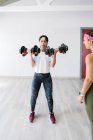 Fitnesstrainerin sucht reife Frau beim Training mit Kurzhanteln im Fitnessstudio — Stockfoto