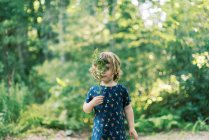 Two year old toddler playing with a fern leaf in the woods — Stock Photo