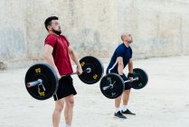 Two weightlifters lifting weights in an urban environment. — Stock Photo