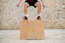 Mann übt Crossfit-Springen in eine Sperrholzbox. — Stockfoto