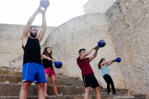 Athletes lifting a kettelbell crossfit weights in an urban enviroment. — Stock Photo