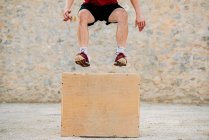 Hombre practicando crossfit saltando en una caja pliométrica. - foto de stock