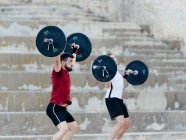 Two weightlifters lifting weights in an urban environment. — Stock Photo