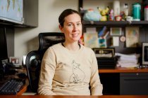 Eine Professorin sitzt in ihrem Büro an einem Schreibtisch und lächelt — Stockfoto