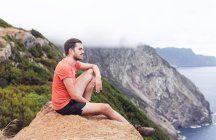 Um homem numa rocha, olhando para falésias e oceanos, montanhas e nevoeiro — Fotografia de Stock
