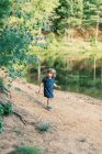Una niña de dos años explorando un estanque local en el bosque - foto de stock