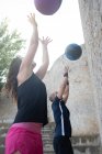 Couple throwing a medicine ball on a wall to practice crossfit. — Stock Photo