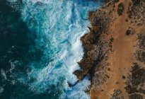 Vista aerea dall'alto delle onde del mare che colpiscono rocce sulla spiaggia — Foto stock