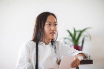 Молодая азиатская женщина-врач с докладом в практике — стоковое фото