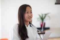 Joven asiático mujer médico con informe en un práctica - foto de stock