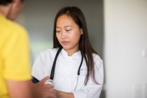 Mujer joven asiática médico con pacientescon informe en una práctica - foto de stock