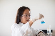 Científico hembra con muestra y tubos en un laboratorio - foto de stock