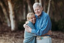 Portrait of retired adult couple hugging in forest — Stock Photo