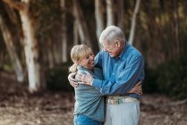 Portrait of senior adult couple hugging in forest — Stock Photo