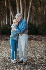Porträt eines erwachsenen Rentnerehepaares, das sich im Wald umarmt — Stockfoto