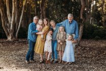 Retrato de una gran familia extendida sonriente abrazándose afuera en el bosque - foto de stock