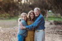 Ritratto di donna adulta e genitori anziani che si abbracciano al parco — Foto stock