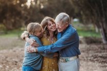 Retrato de mulher adulta e pais idosos abraçando no parque — Fotografia de Stock