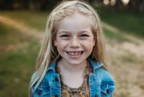 Primer plano retrato de la niña de edad escolar sonriendo fuera - foto de stock