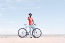 Side view of African American male cyclist riding bike on sunny embankment — Stock Photo