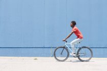 Vista lateral da bicicleta de equitação de ciclista masculino afro-americano no dique ensolarado — Fotografia de Stock