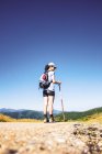 Frau wandert auf Straße gegen Berglandschaft und blauen Himmel — Stockfoto