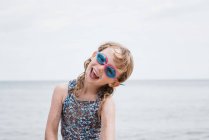 Молода дівчина сміється зі своїми окулярами під час гри на пляжі — стокове фото