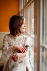 Счастливая девушка смотрит в окно с цыпочкой на руках — стоковое фото