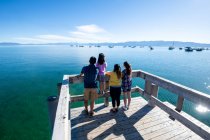 A family looks out on the calm waters of Lake Tahoe from a pier on a sunny summer day in South Lake Tahoe, California. — Stock Photo