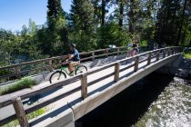 Une famille traverse un pont au-dessus du ruisseau Taylor à vélo par une belle journée d'été près de South Lake Tahoe, Californie. — Photo de stock