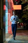 Giovane uomo d'affari cammina con il suo smartphone e tazza di caffè — Foto stock