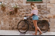 Красива молода жінка з велосипедом у місті — стокове фото