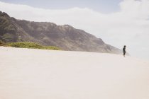 Frau steht allein auf einem sandigen Hügel vor einem Berg — Stockfoto