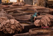 Hombre trabajando con pieles de cuero en curtiduría en fez, Marruecos - foto de stock