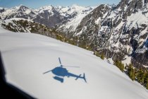 Тінь вертольота видно на засніженому гірському ландшафті — стокове фото