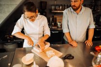 Köchin in Uniform arbeitet mit Assistentin in Restaurantküche — Stockfoto