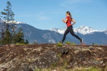 Женщина-атлет, бегущая возле гор — стоковое фото