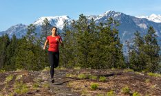 Atleta feminina correndo perto de montanhas — Fotografia de Stock