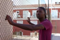 Молодий африкансько-мериканський чоловік тримає паркан на вулиці. — стокове фото