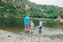 Сім'я грає у воді в мальовничому місці річки — стокове фото