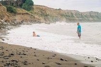 Vater und sohn boogie boarding am strand — Stockfoto