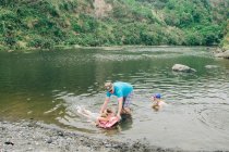 Família em um ponto de rio cênico brincando na água — Fotografia de Stock