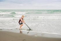 Young boy playing on the beach with his skim board — Stock Photo